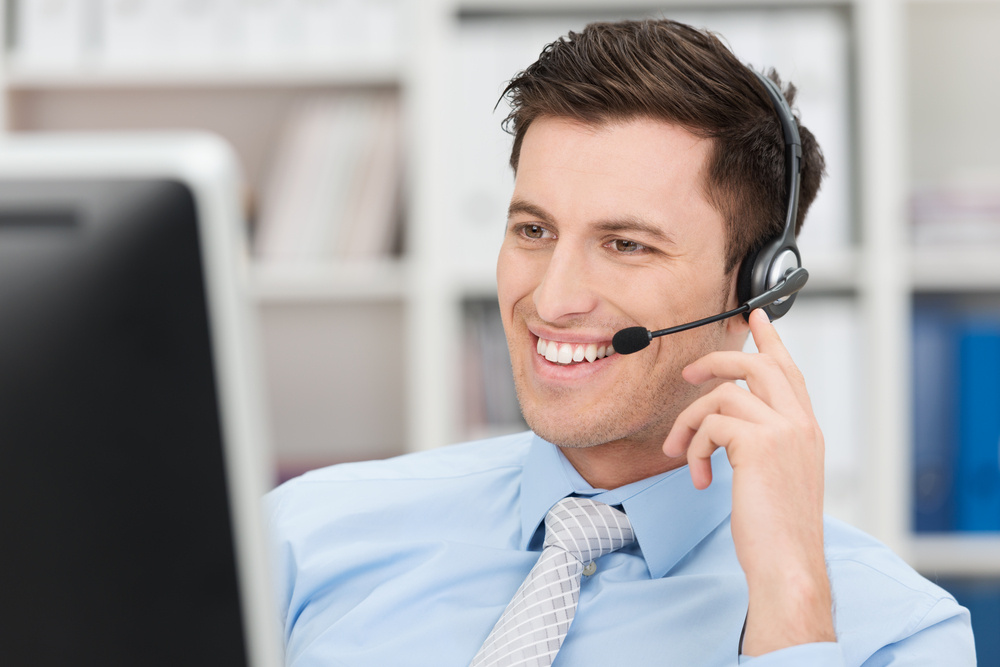 Smiling friendly young male call centre operator or client services personnel 
